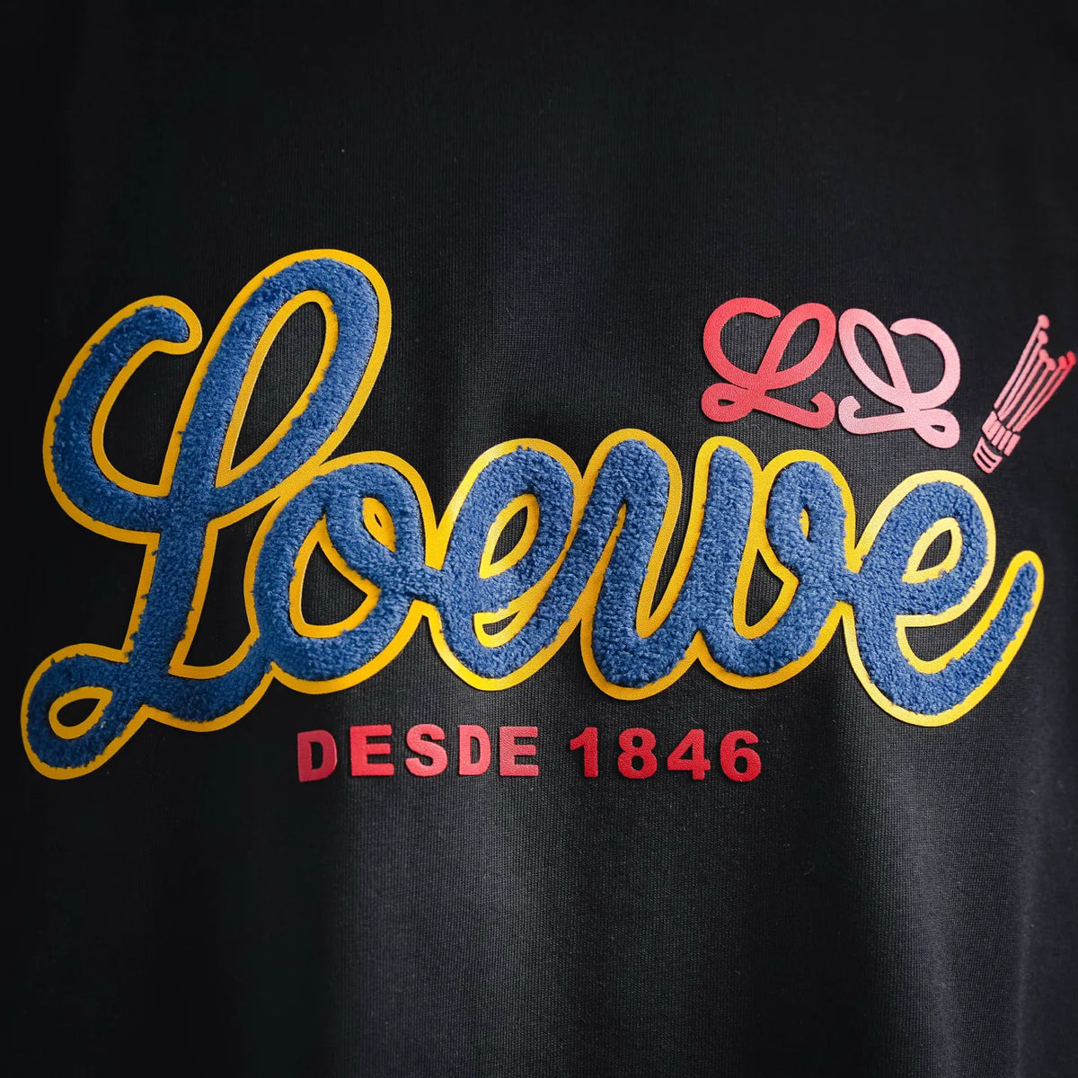Black T-shirt with large colorful “LOEWE DESDE 1846” logo graphic