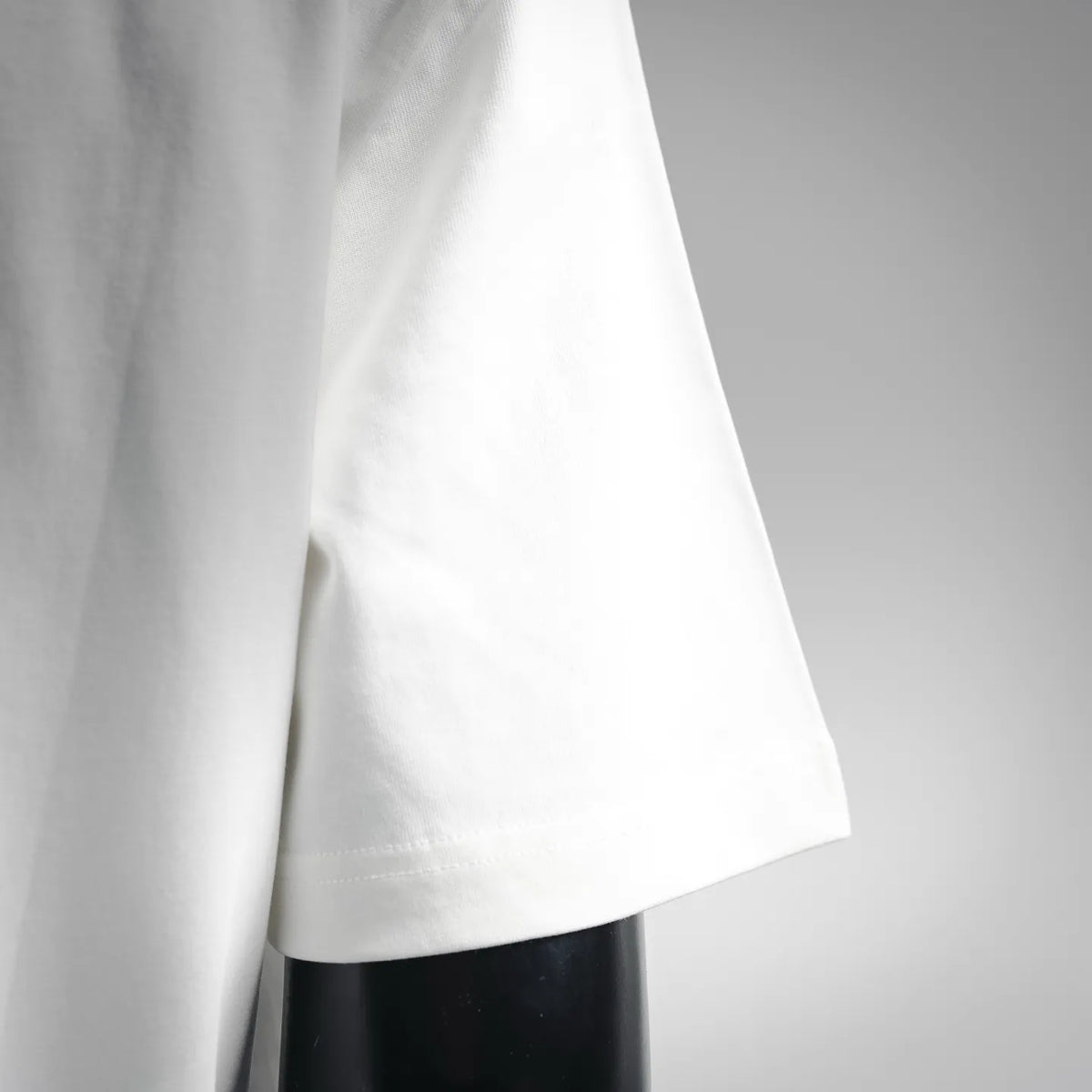 White T-shirt side seam and curved hem, short sleeves visible.