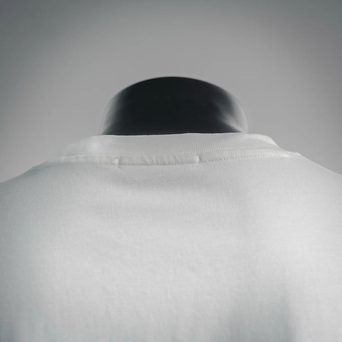 White T-shirt back neckline detail with inner stitching on mannequin.