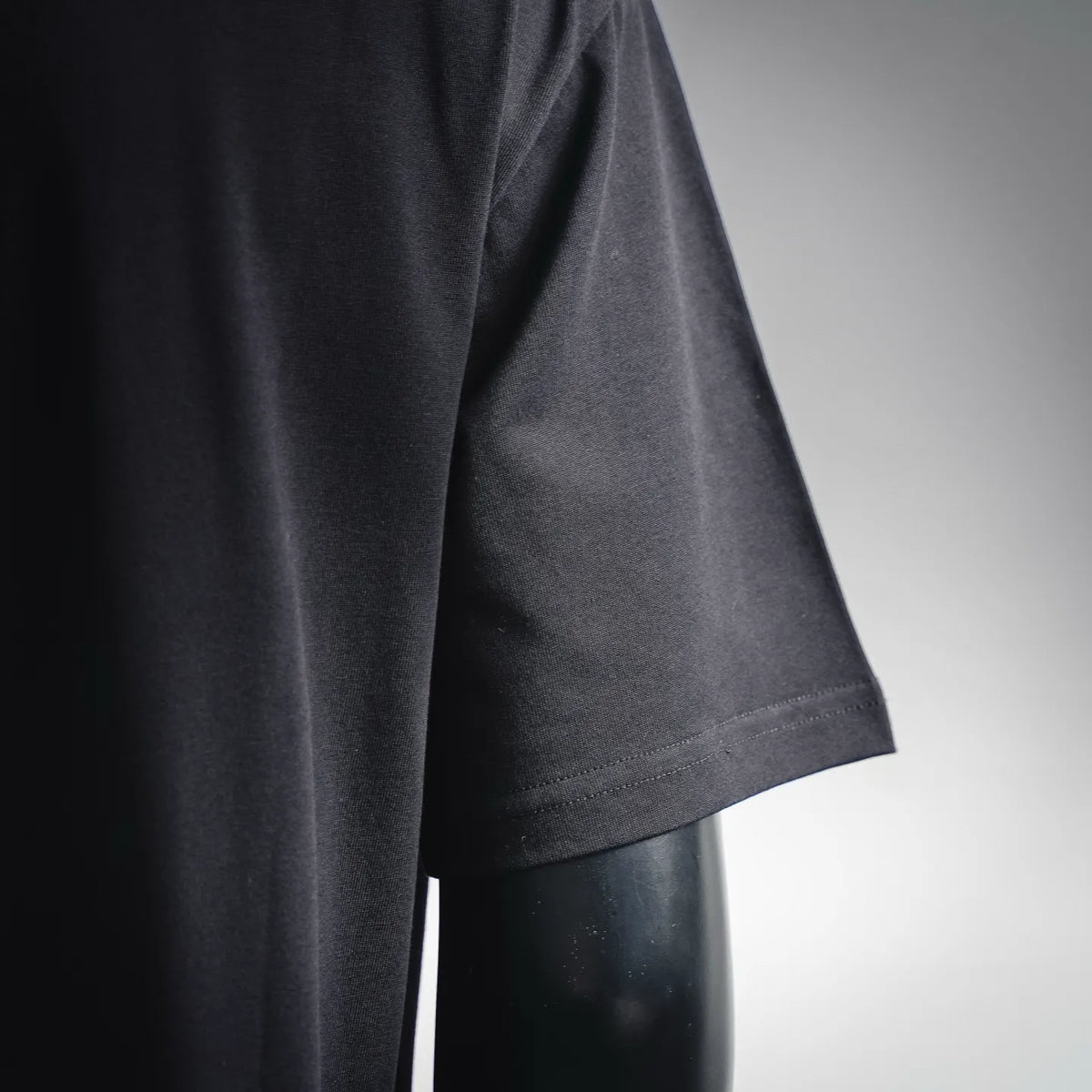 LOEWE dark T-shirt fabric and hem detail, short sleeve edge visible.
