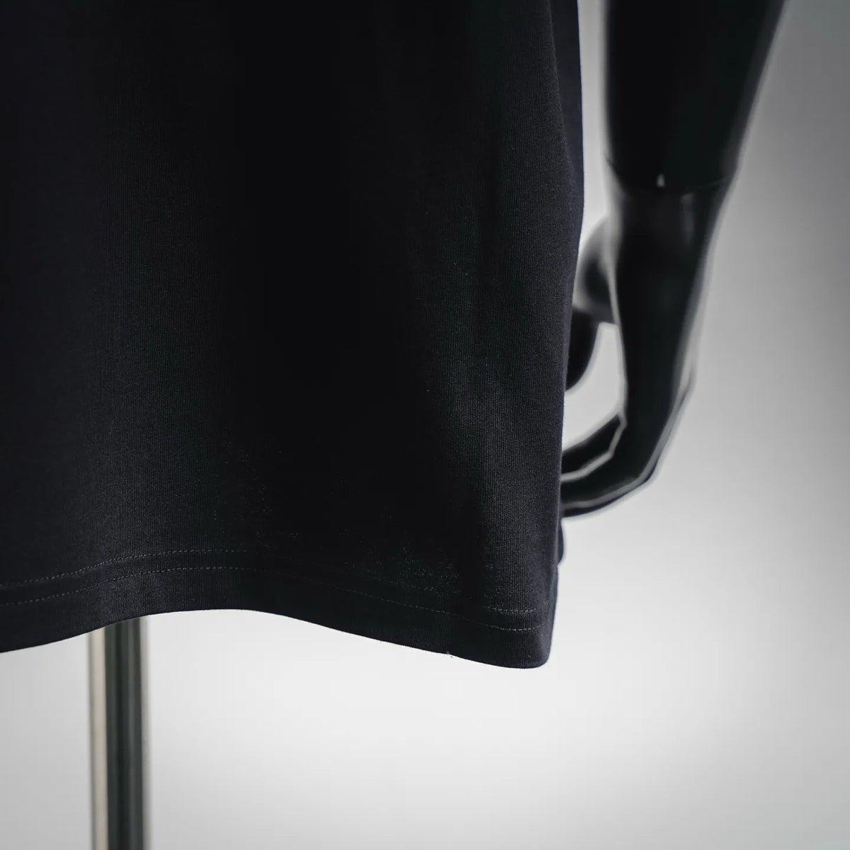 LOEWE dark T-shirt side view with short-sleeve hem and drape detail.