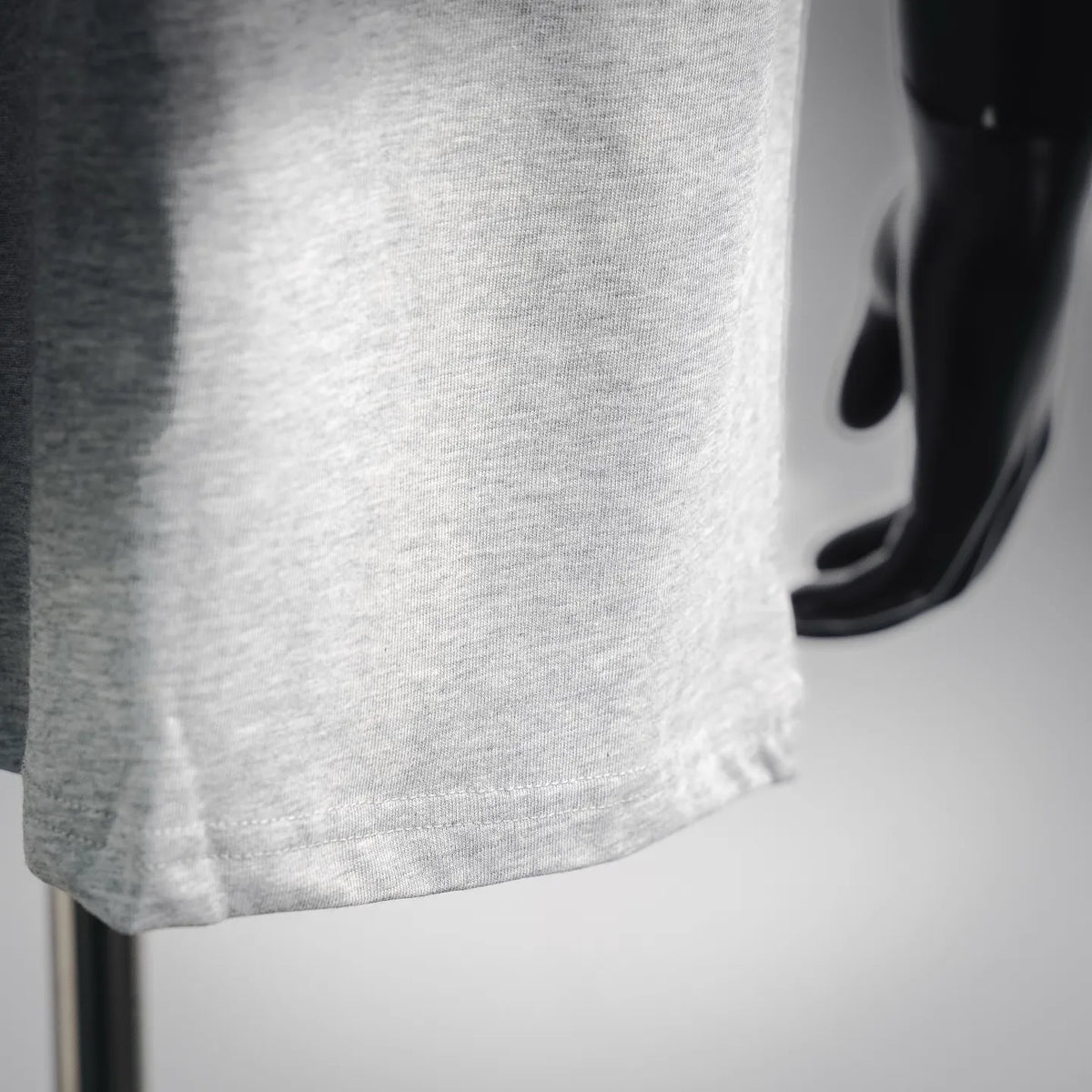 Grey short-sleeve T-shirt fabric close-up, clean hem and stitching detail