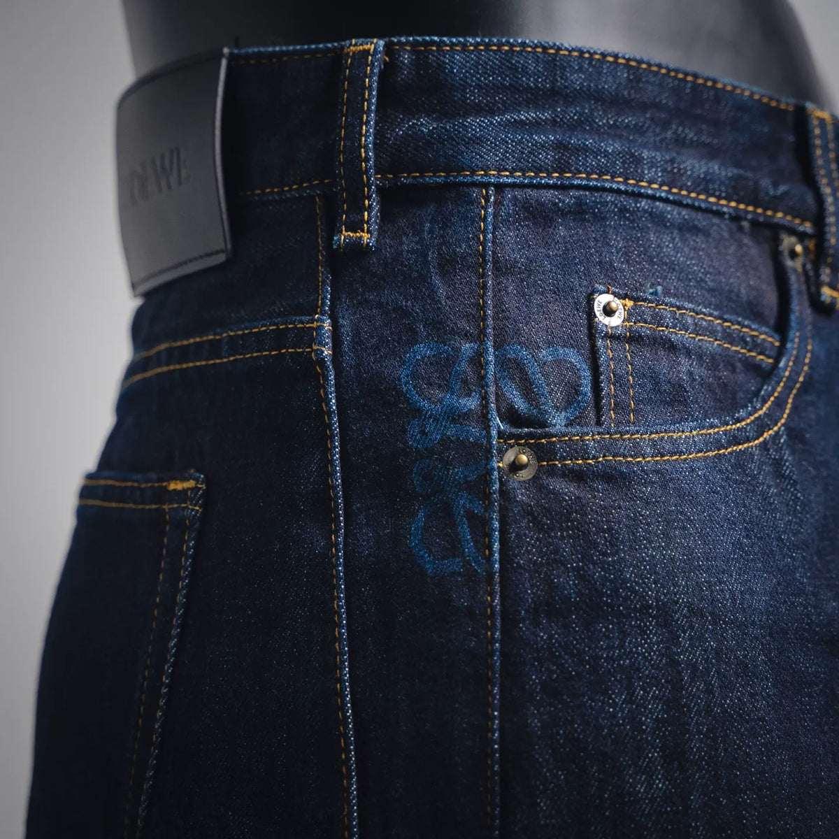Dark blue denim pants with metal button closure and stitched coin pocket