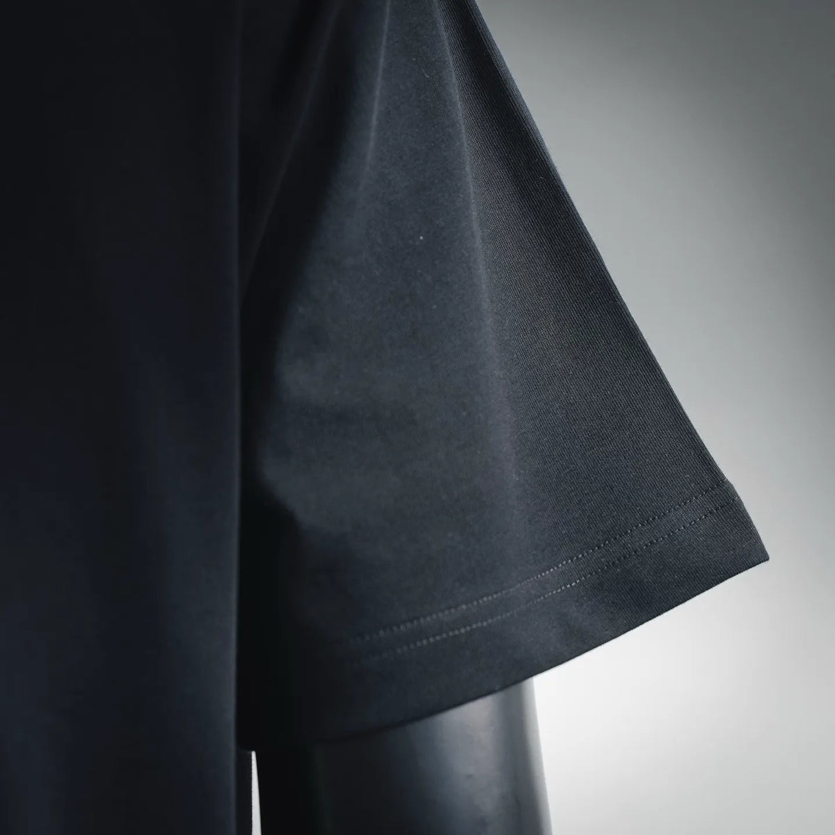 Black short-sleeve T-shirt with stitched sleeve hem, side view.