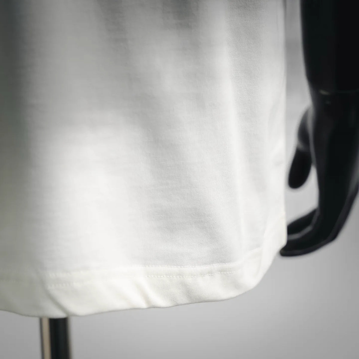 White short-sleeve T-shirt fabric close-up at the lower front hem