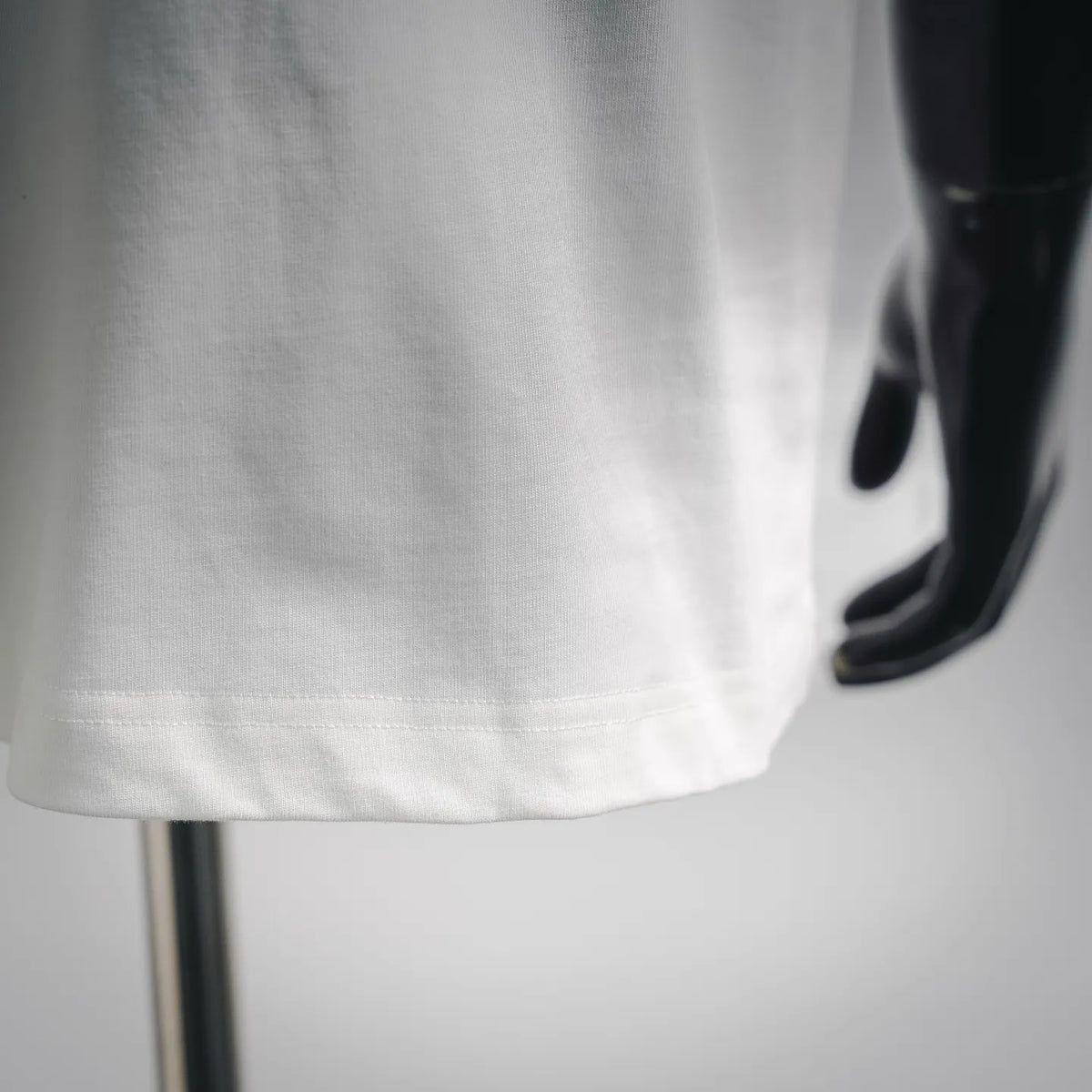 White T-shirt hem with visible stitching at bottom edge