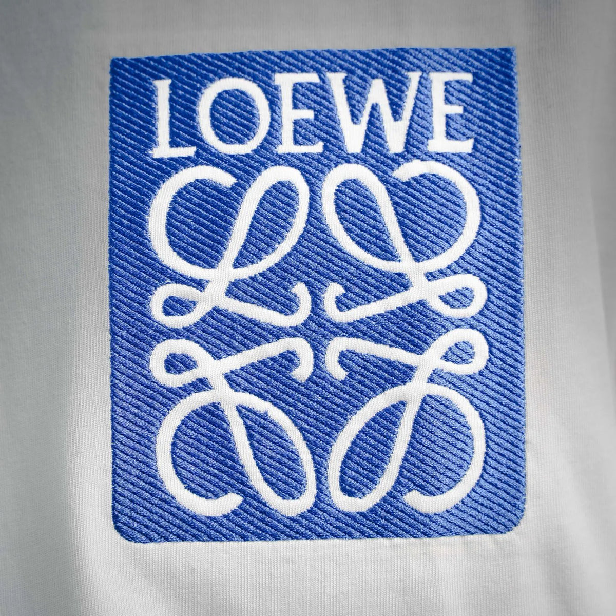 Blue square LOEWE logo embroidery patch on white T-shirt chest
