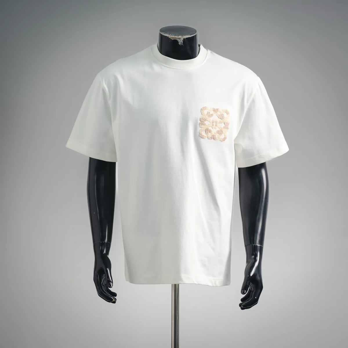 White short-sleeve T-shirt with small beige logo patch on left chest
