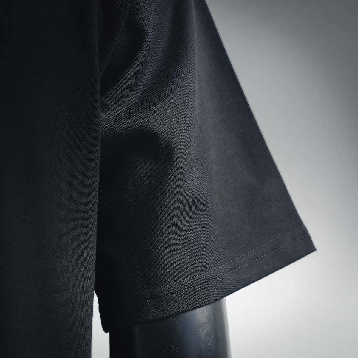 Black short-sleeve T-shirt with stitched sleeve hem detail.