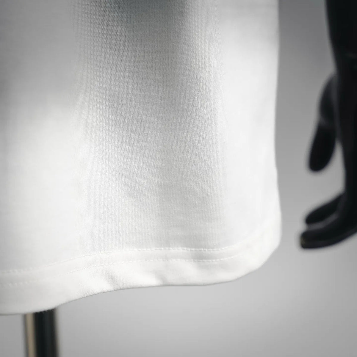 Close-up of white T-shirt hem with visible double stitching and fabric texture