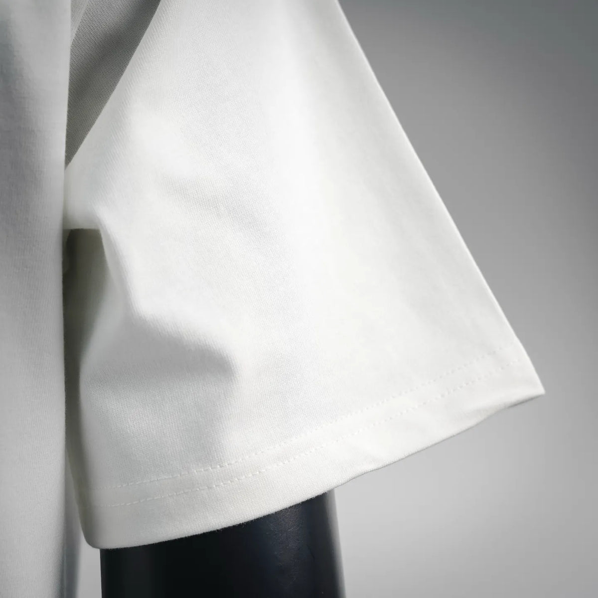 Side view of white short-sleeve T-shirt showing curved hemline and seams