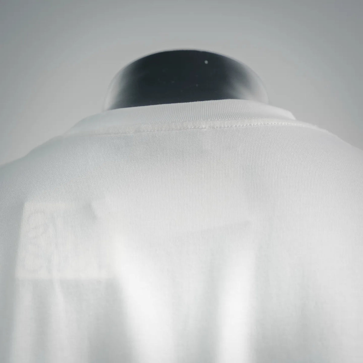 Close-up of white T-shirt back collar area with smooth fabric and neckline seam