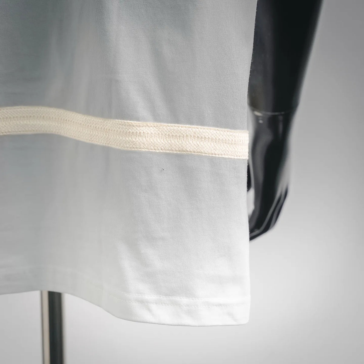 Close-up of white T-shirt hem with beige stripe trim