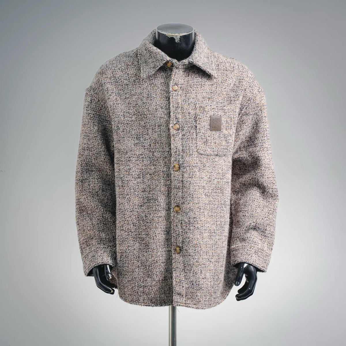 Beige tweed coat with button front, pointed collar, and chest patch pocket.