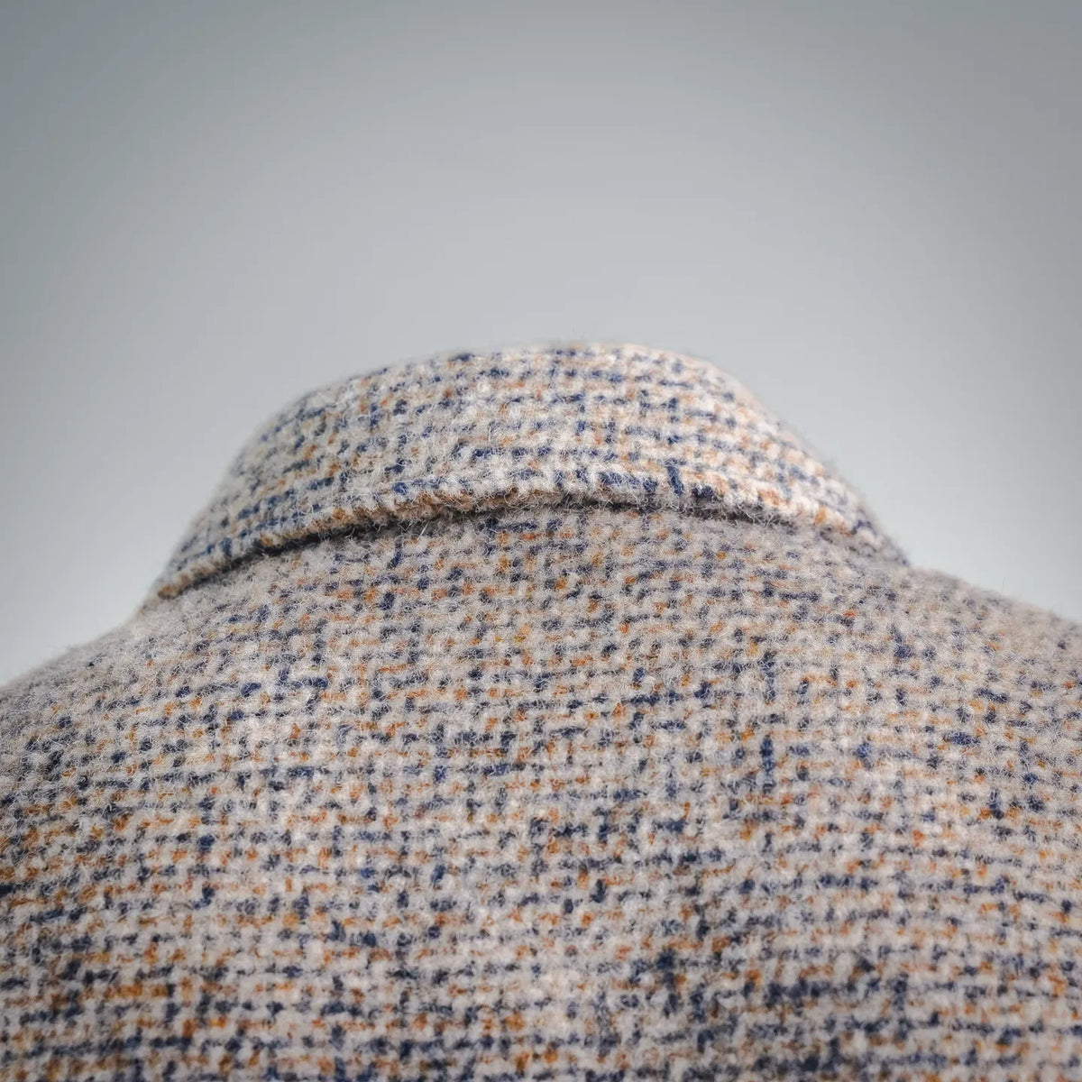 Beige tweed coat collar detail with dense wool texture.