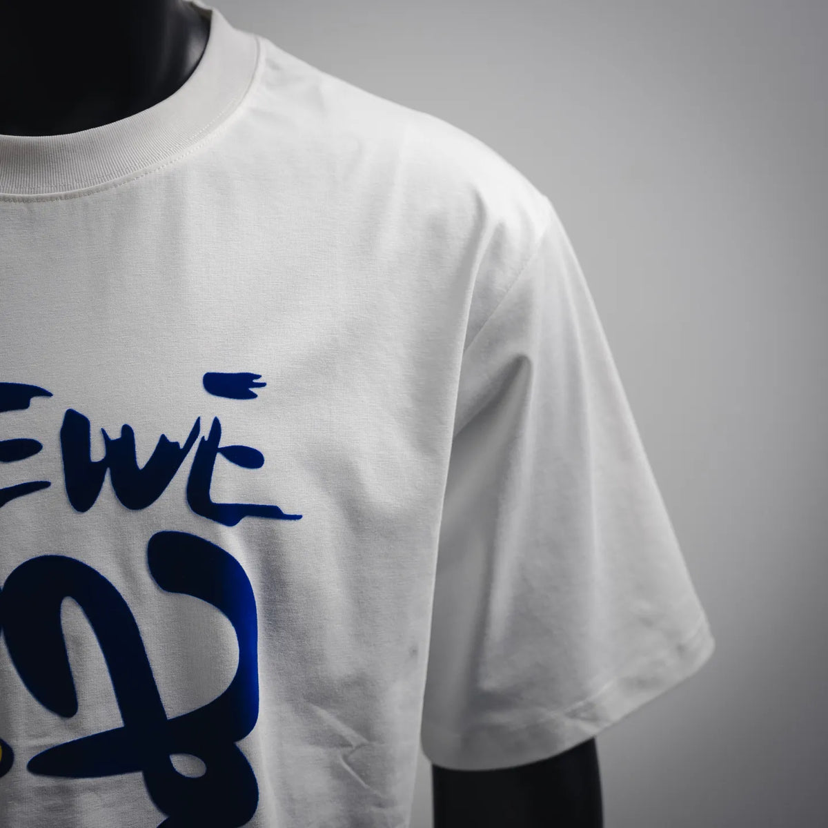 White T-shirt sleeve with blue LOEWE-style graffiti print detail