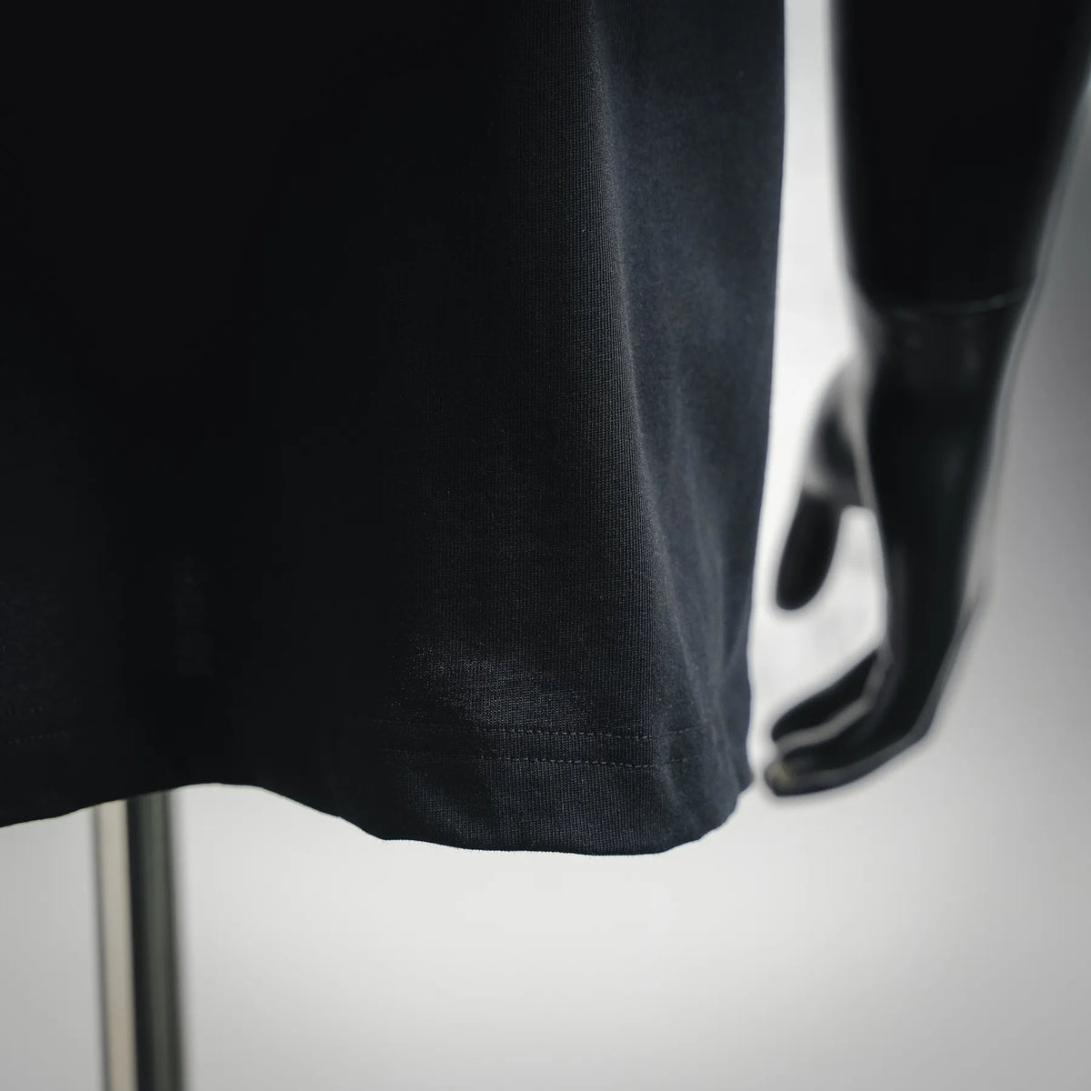 Black crewneck T-shirt hem with stitched detail, close-up
