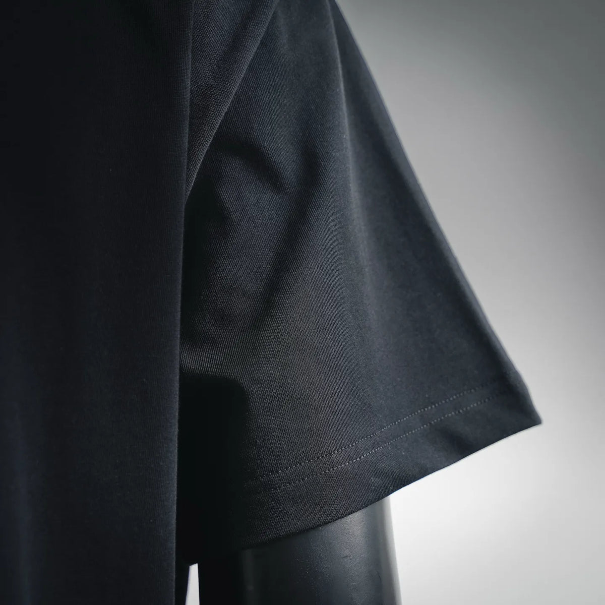 Black short-sleeve T-shirt with curved hem, fabric close-up