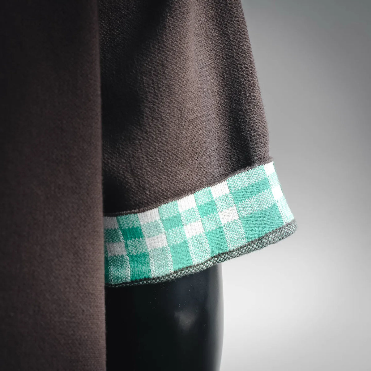 Short-sleeve shirt cuff detail with teal check trim and dark knit sleeve