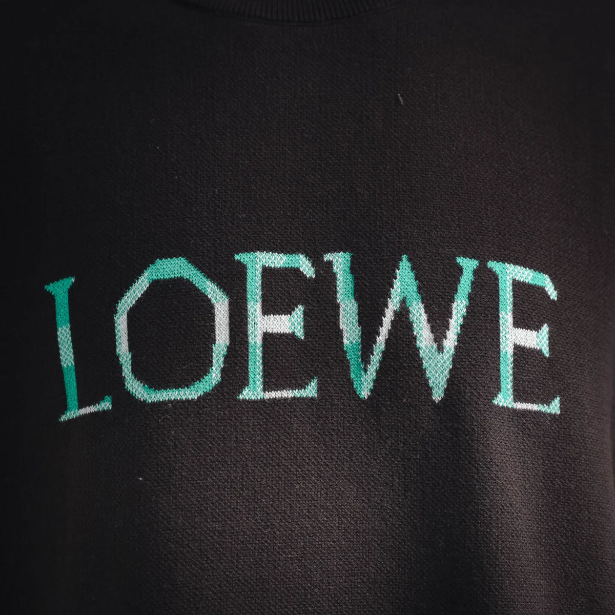LOEWE logo on dark short-sleeve shirt in teal lettering