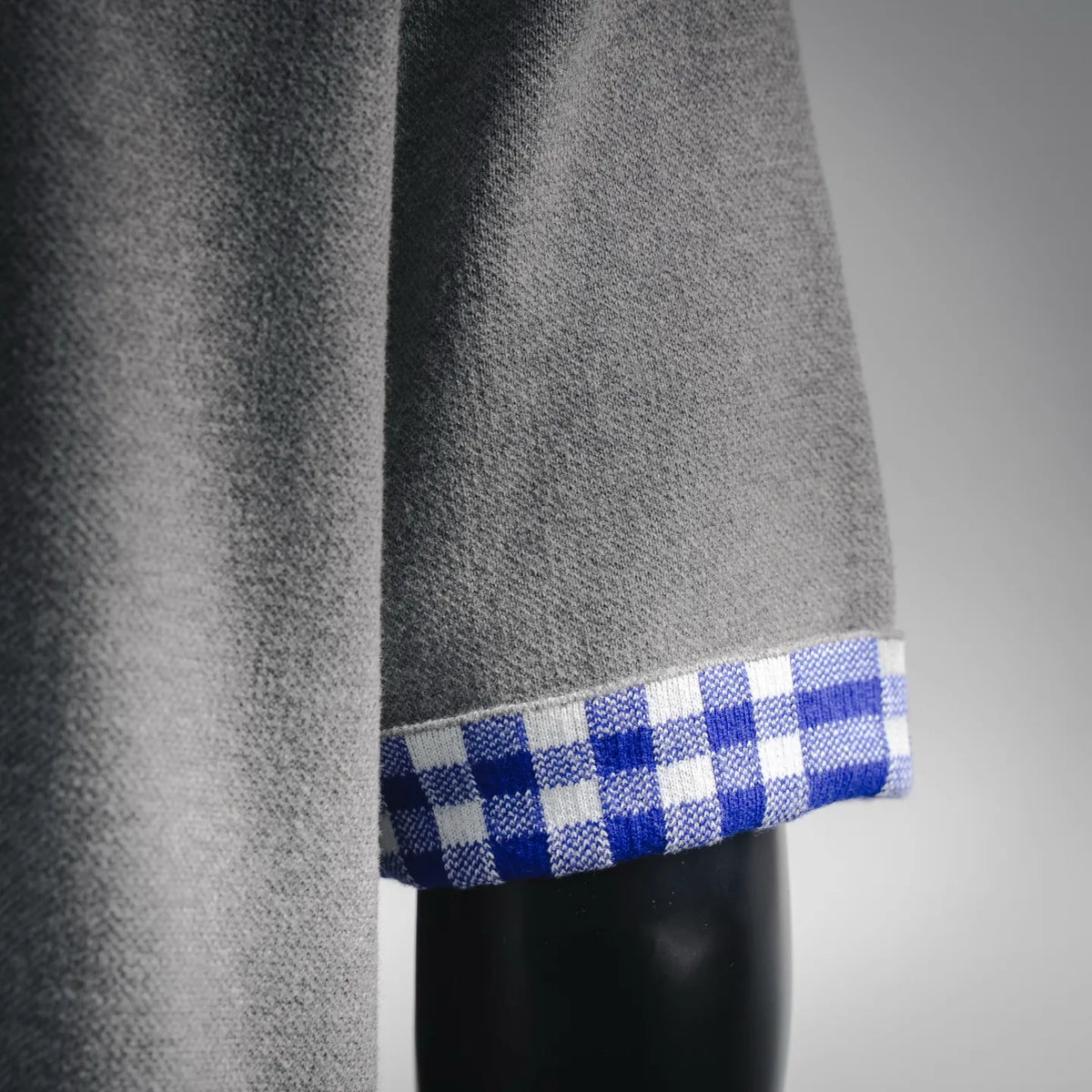 Grey knit fabric with blue and white checkered cuff trim