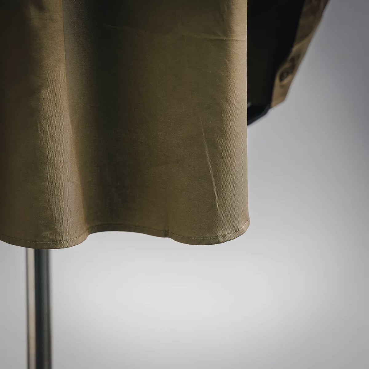 Men's long-sleeve button-up shirt hem and side, olive/khaki close-up