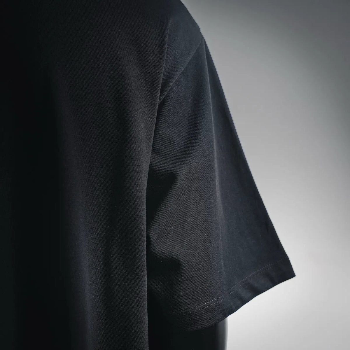 Black T-shirt sleeve with visible fabric texture and stitched hem