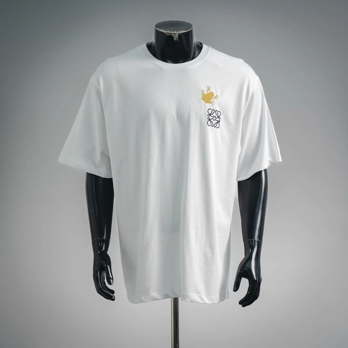 White short-sleeve T-shirt with gold and black embroidered emblem on chest