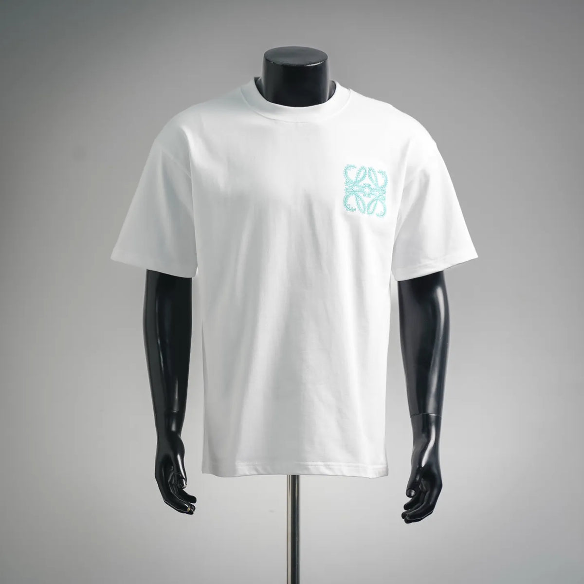 White short-sleeve T-shirt with small teal decorative logo on the chest