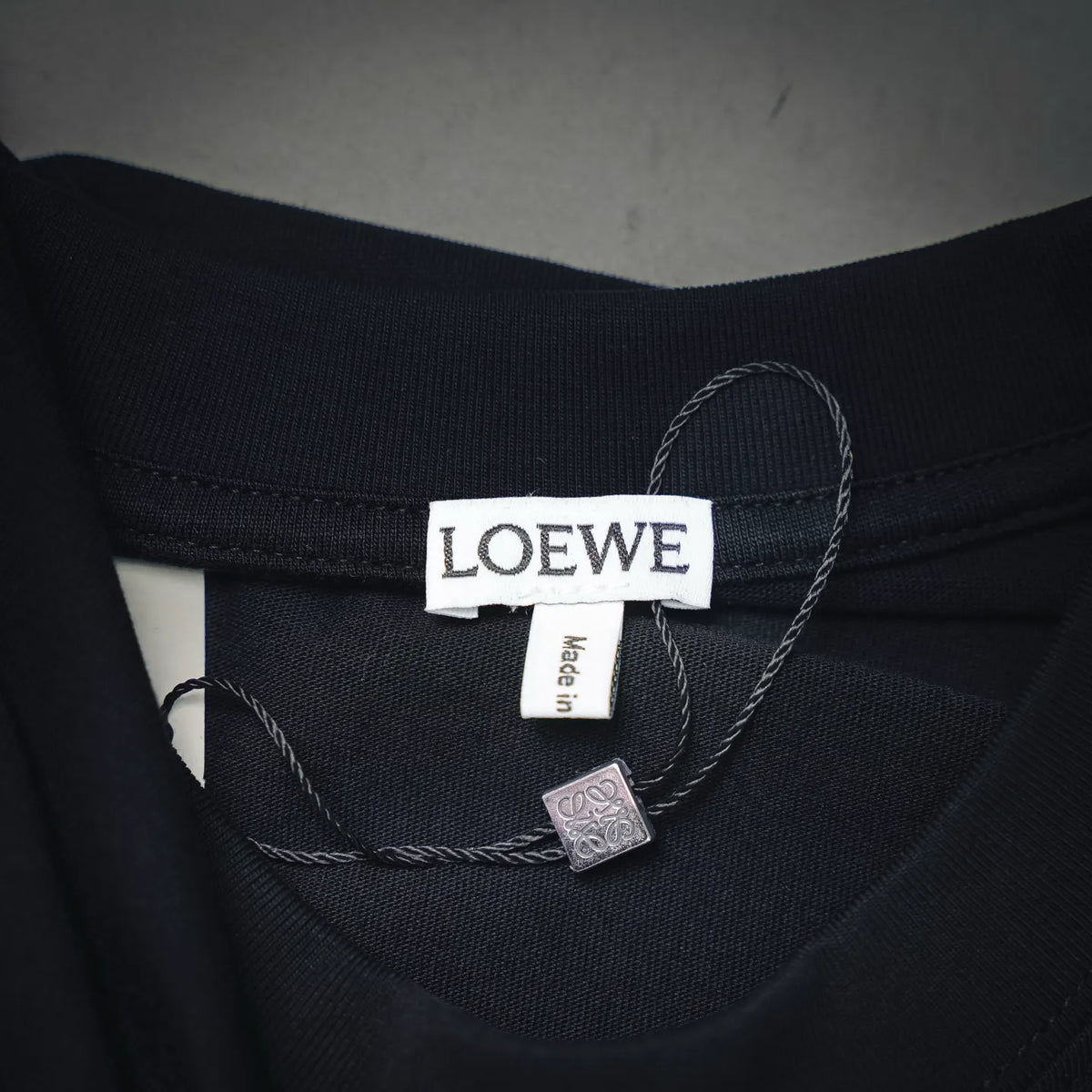 Black crew-neck T-shirt collar label with LOEWE tag and size label