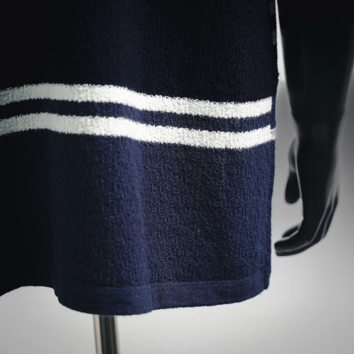 Close-up of navy knit sweater hem with white horizontal stripe bands