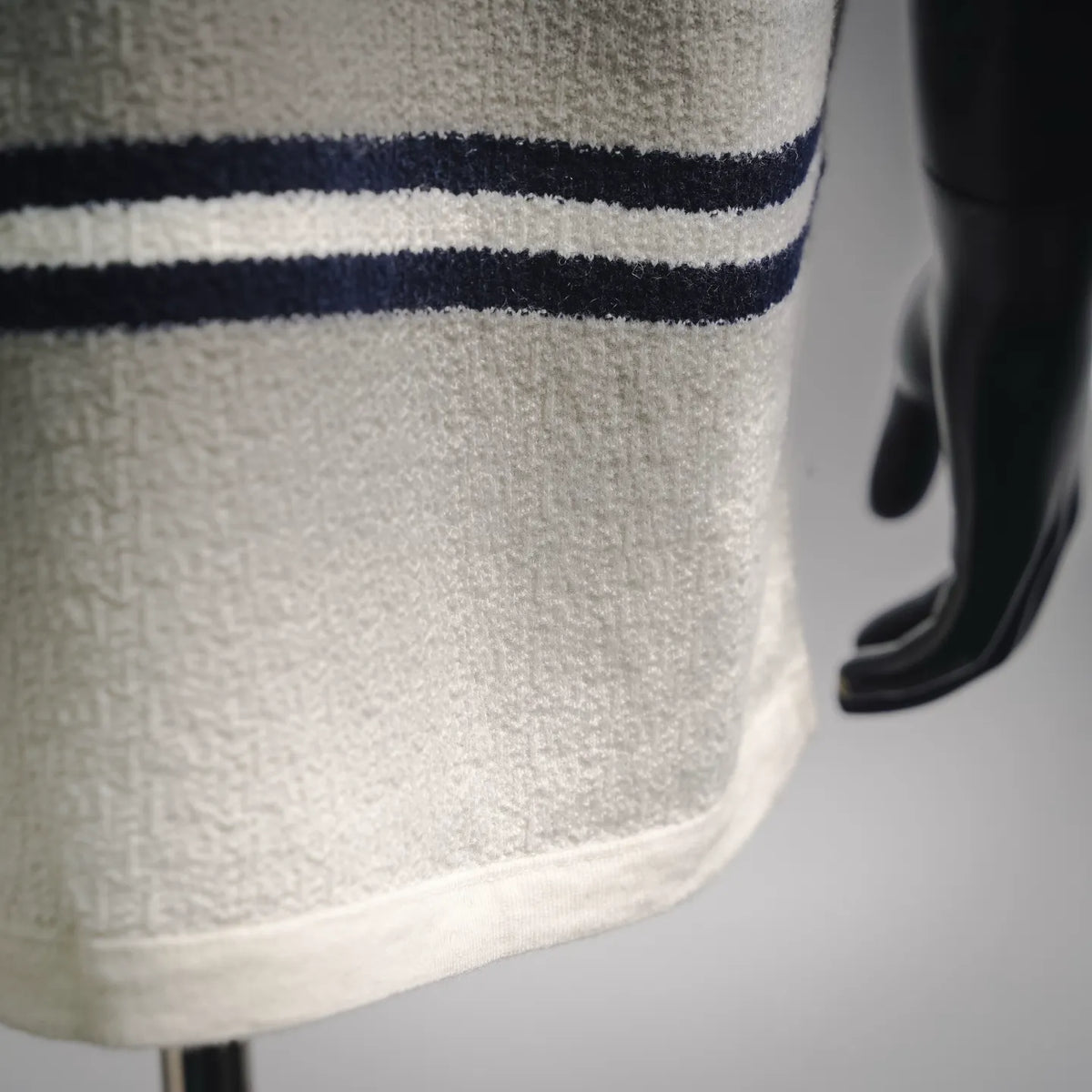 Close-up of white fabric and navy stripe hem detail on short-sleeve shirt