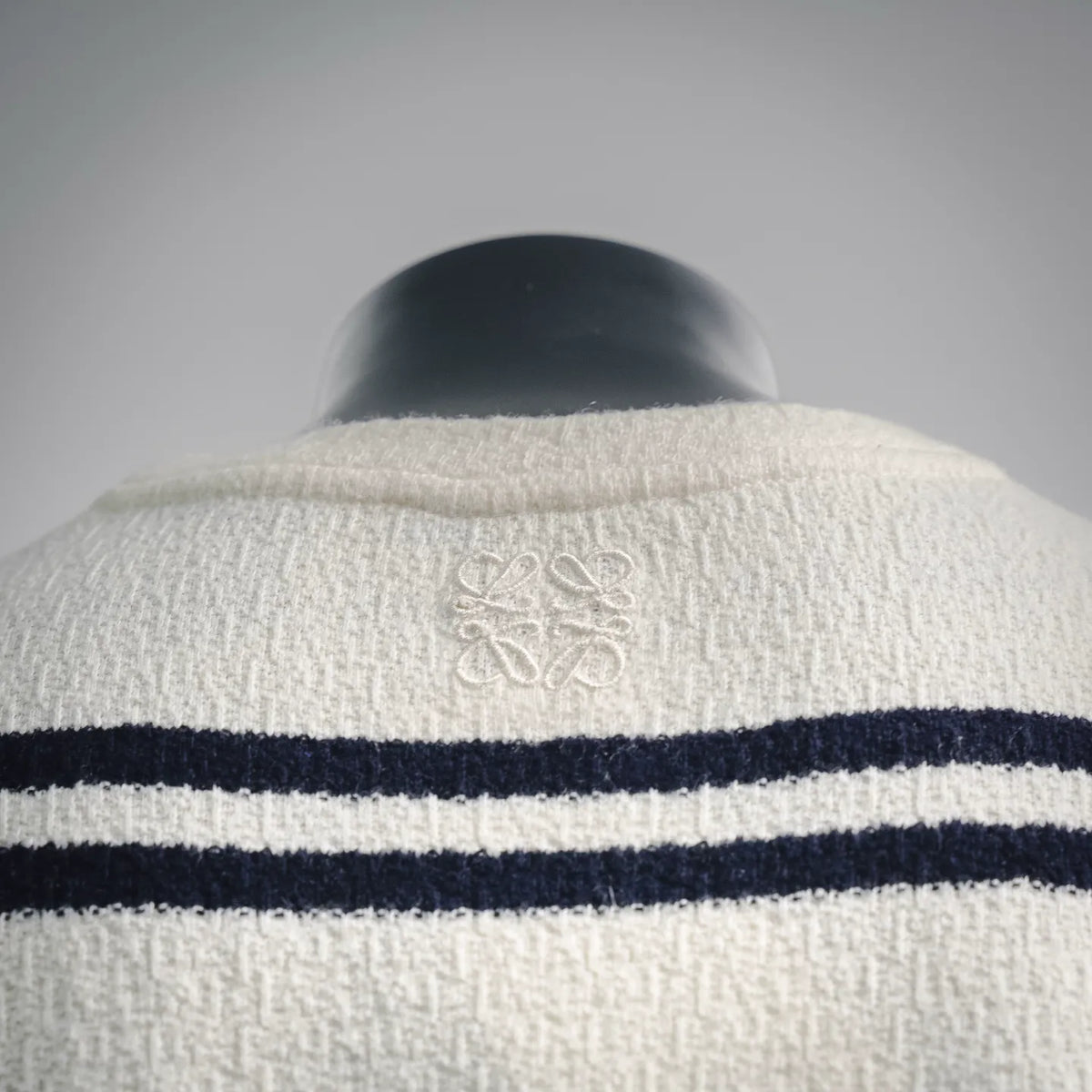 Back collar area with embroidered emblem and navy stripe band on white shirt