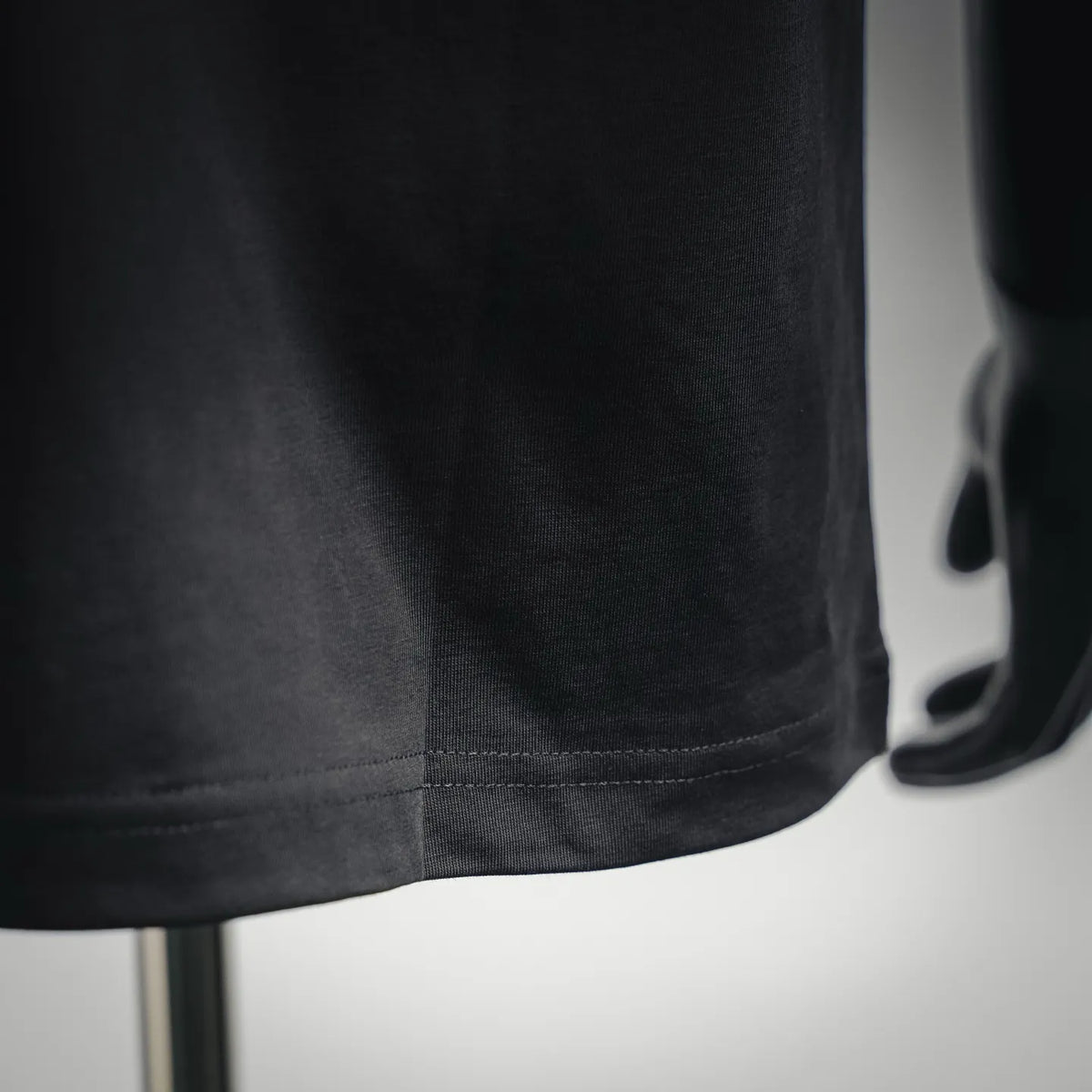 Dark gray T-shirt hem closeup with stitched bottom seam