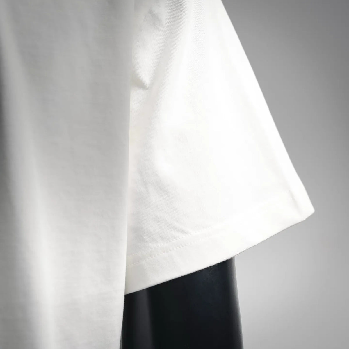 White short-sleeve T-shirt with straight cut, close-up of lower side