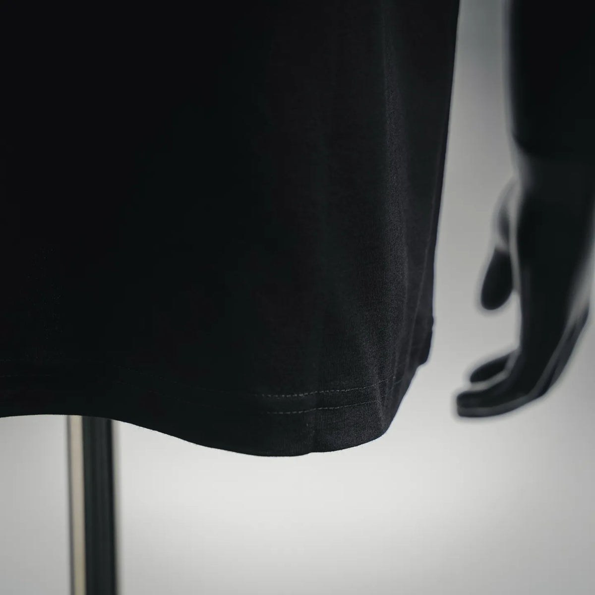 Black T-shirt hem detail with stitched bottom and side seam