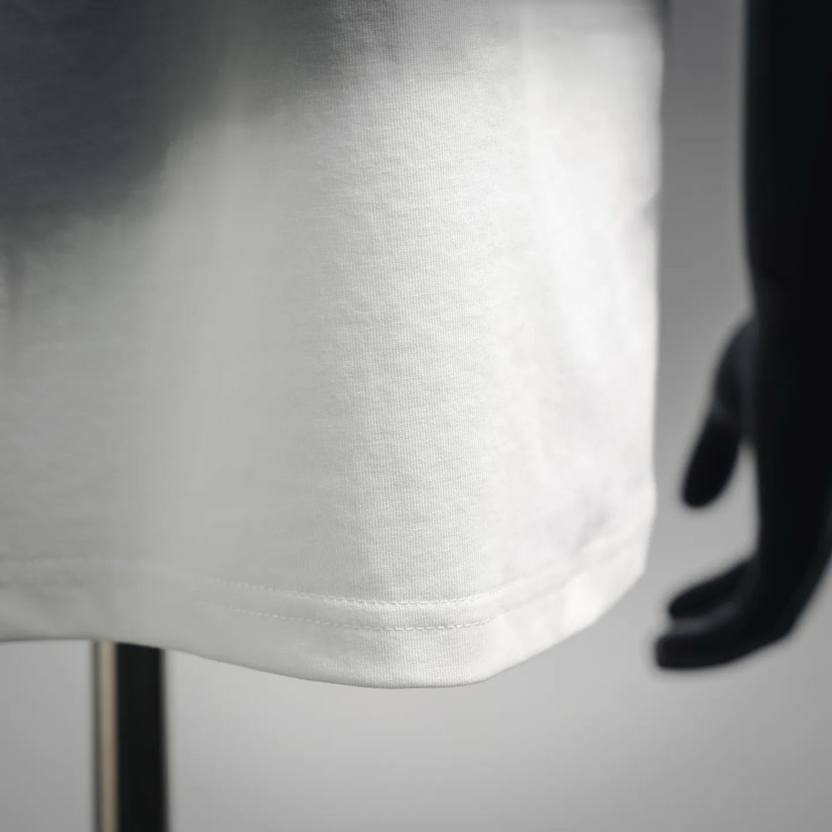 White T-shirt fabric close-up with smooth hem and stitching detail