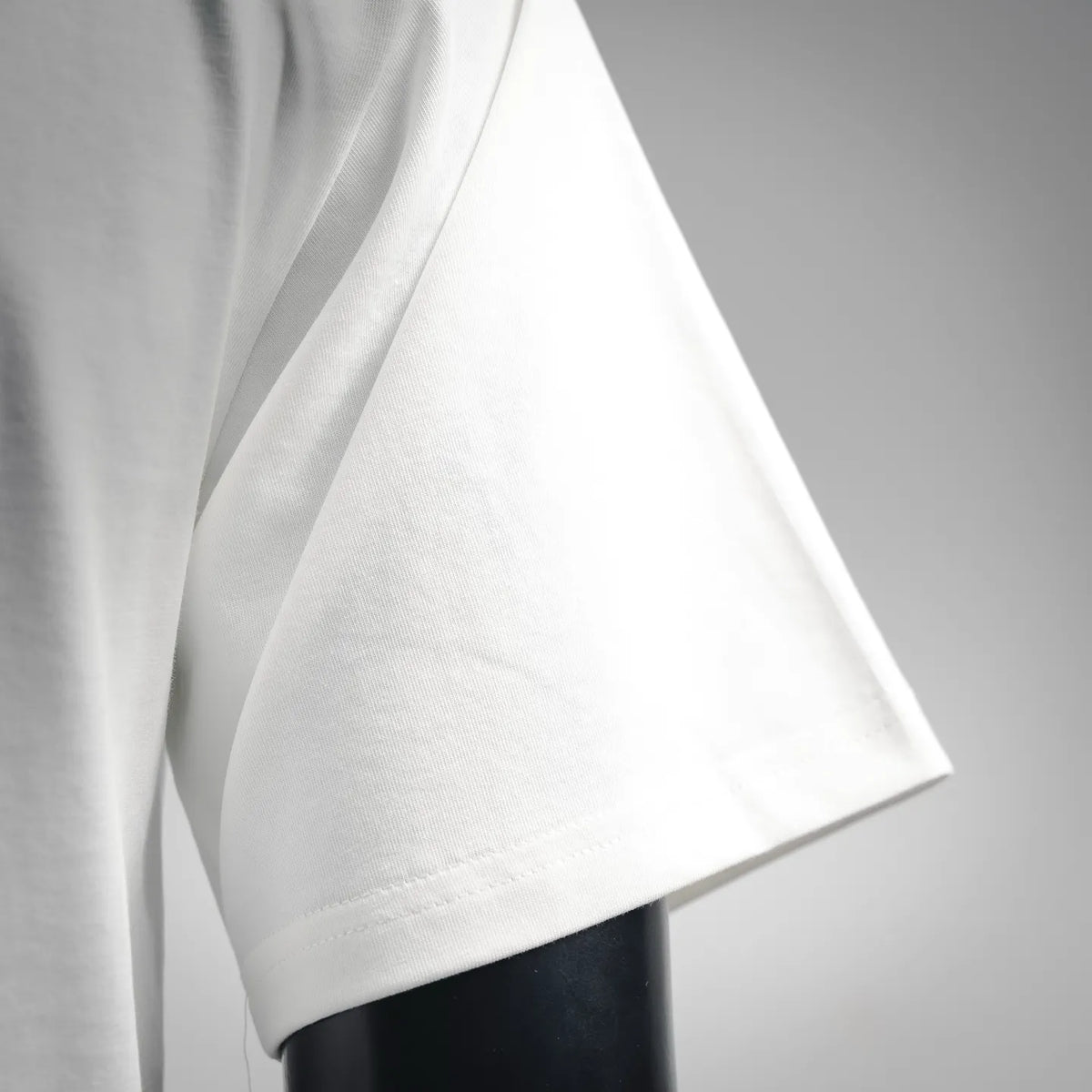 White T-shirt sleeve close-up showing fabric drape and stitched hem