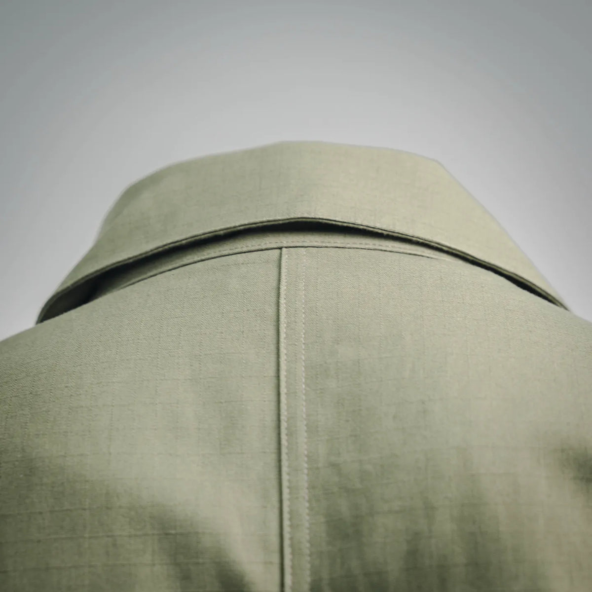 Olive green high collar coat with stitched shoulder seam and top back panel
