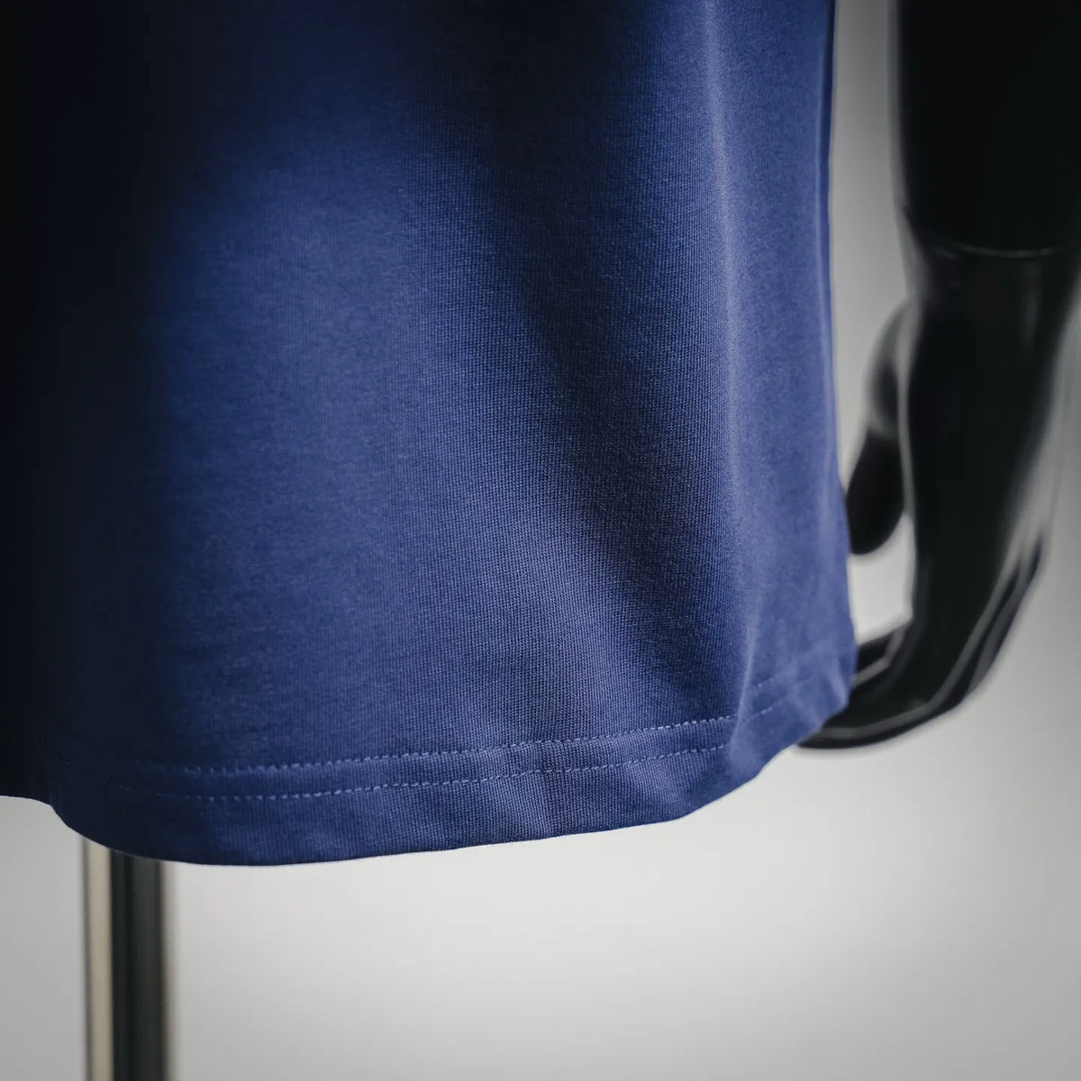 Navy T-shirt hem with stitched edge and curved drape on mannequin