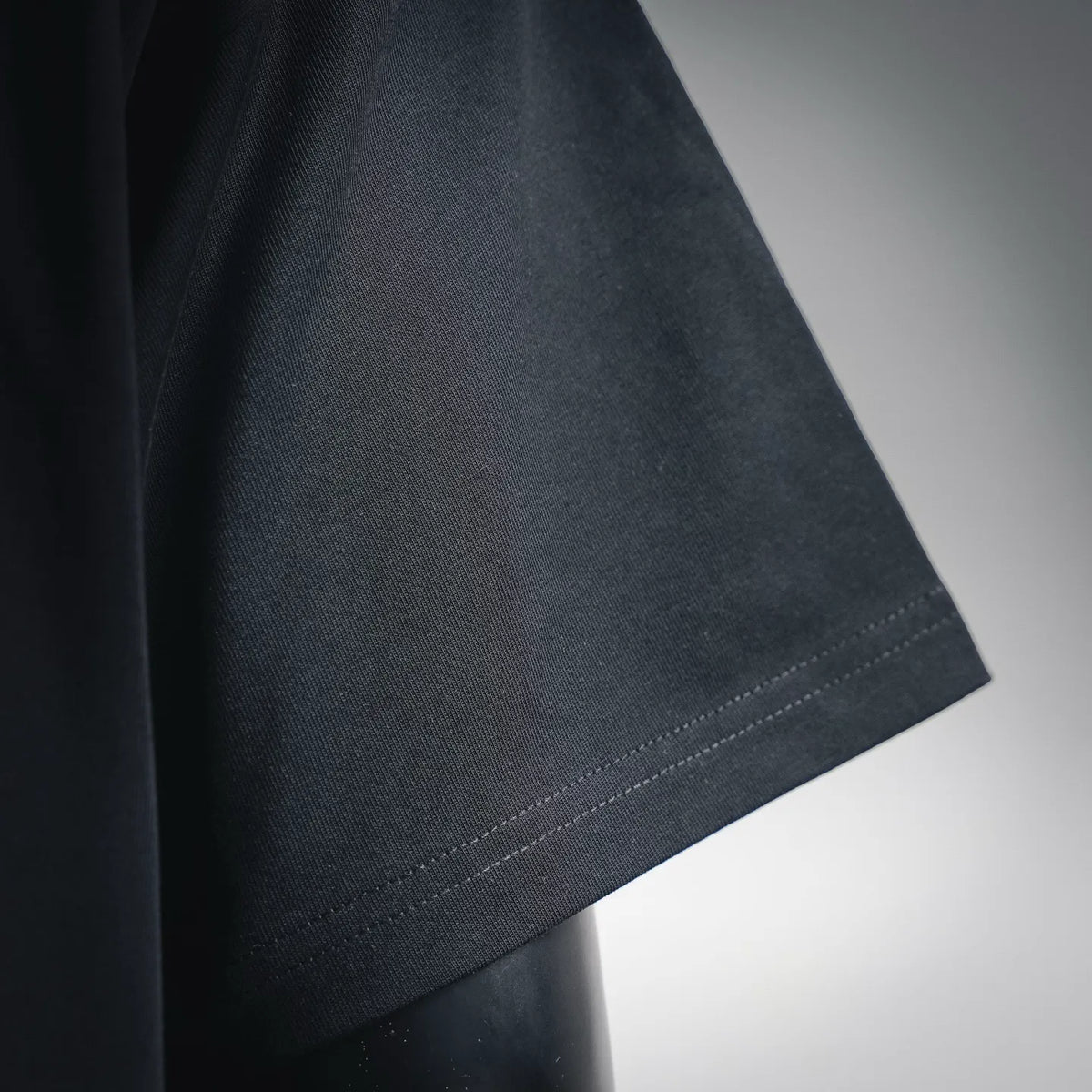 Black short-sleeve T-shirt with curved side seam and stitched hem.