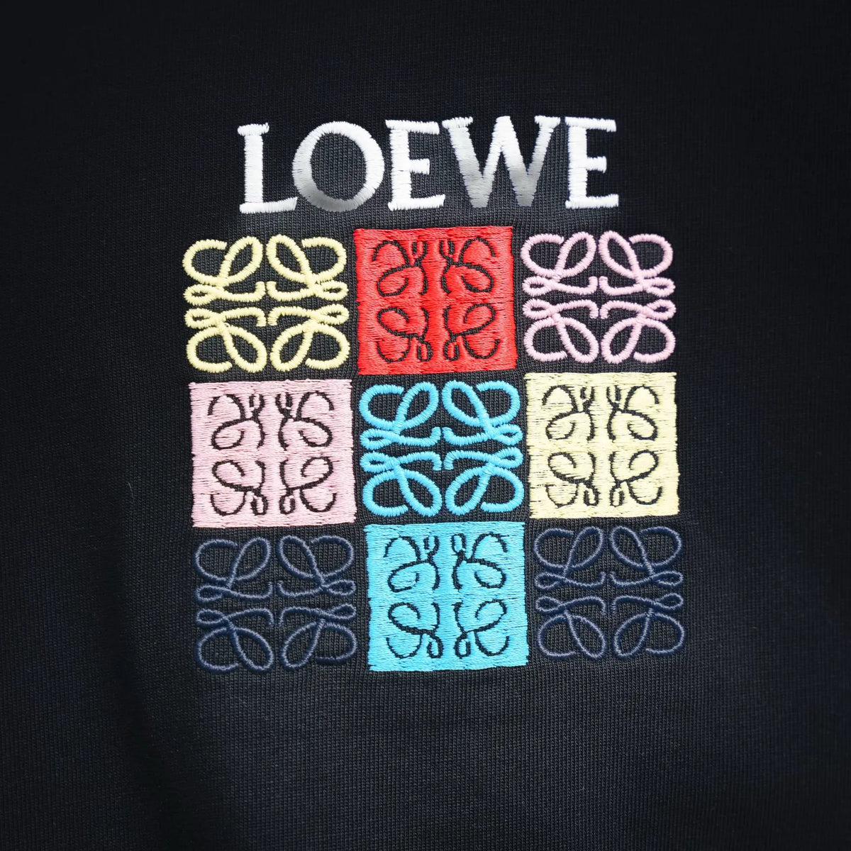 LOEWE chest logo with multicolor puzzle-pattern design on black fabric.