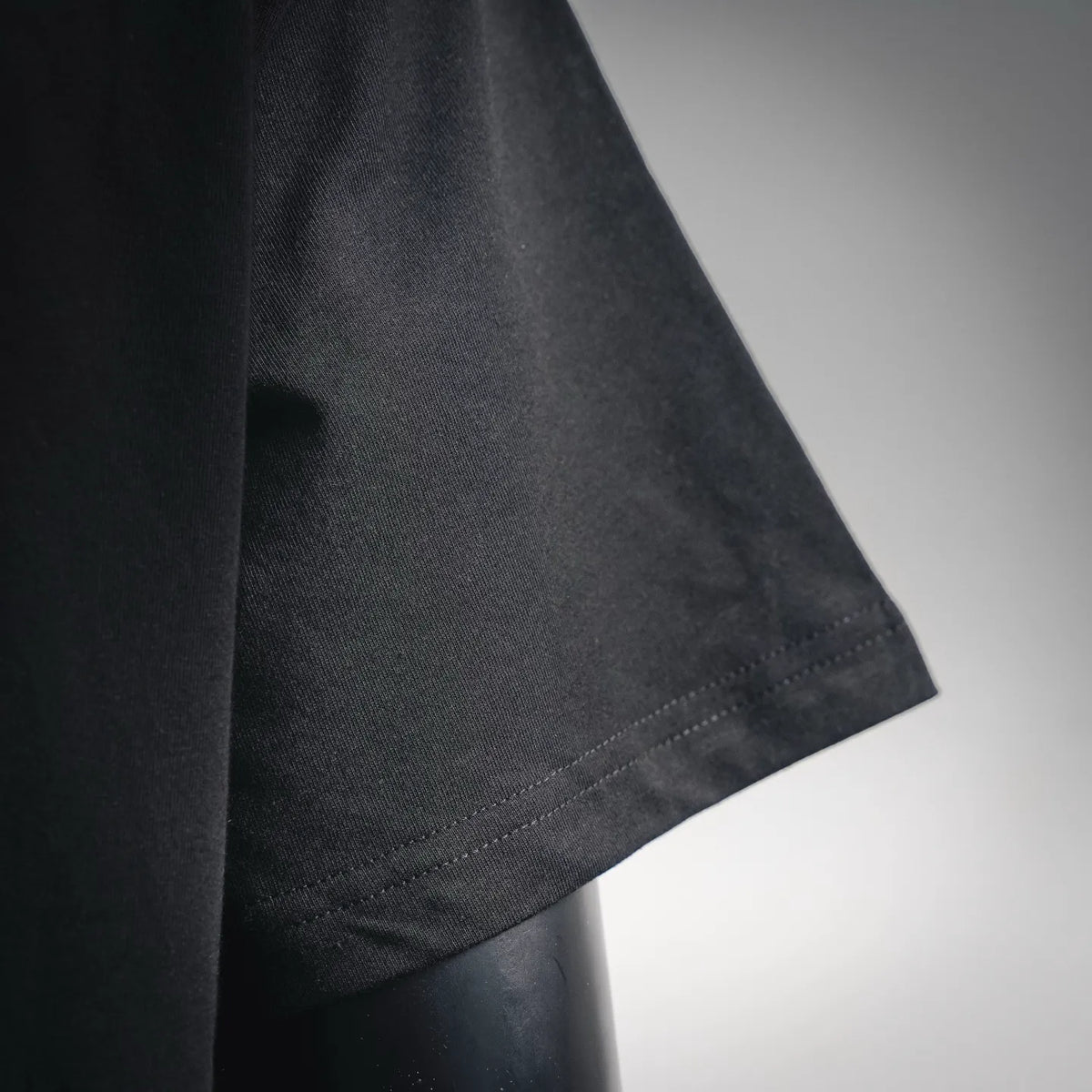 Black T-shirt sleeve close-up with visible hem stitching