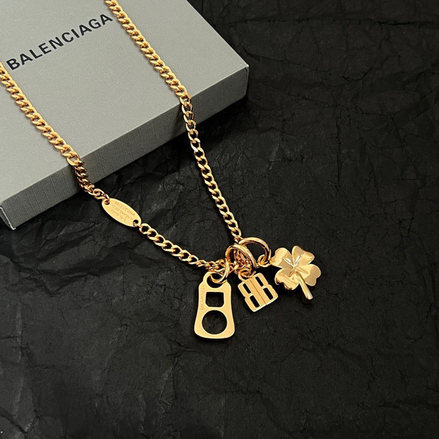 Gold charm necklace with BB, key, and clover pendants on a gold chain