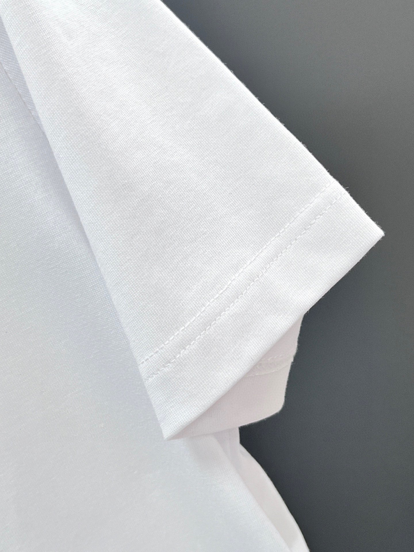 White T-shirt sleeve and hem close-up with stitched cuff