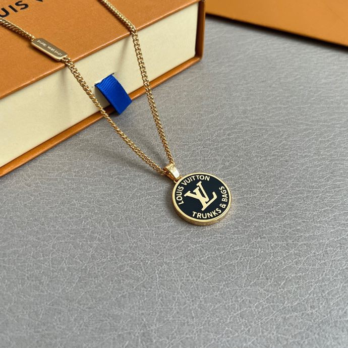 Gold-tone necklace with round logo pendant over a light gray surface