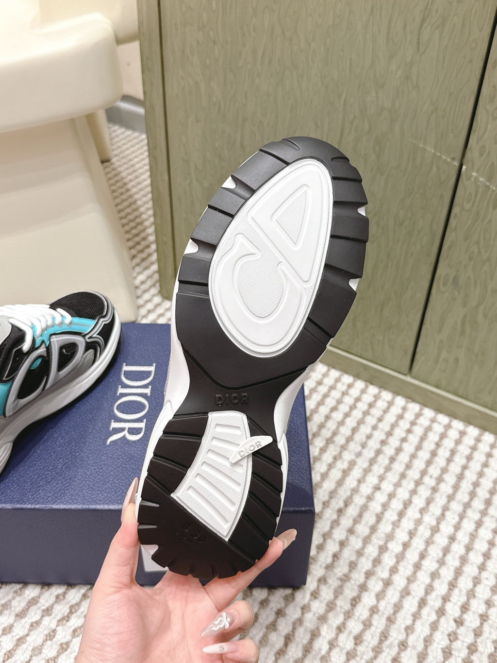 Dior unisex sneaker outsole view, dark rubber tread on black-and-white sole