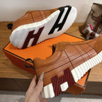 Hermes unisex sneakers outsole view, brown upper with white striped tread and thick sole.