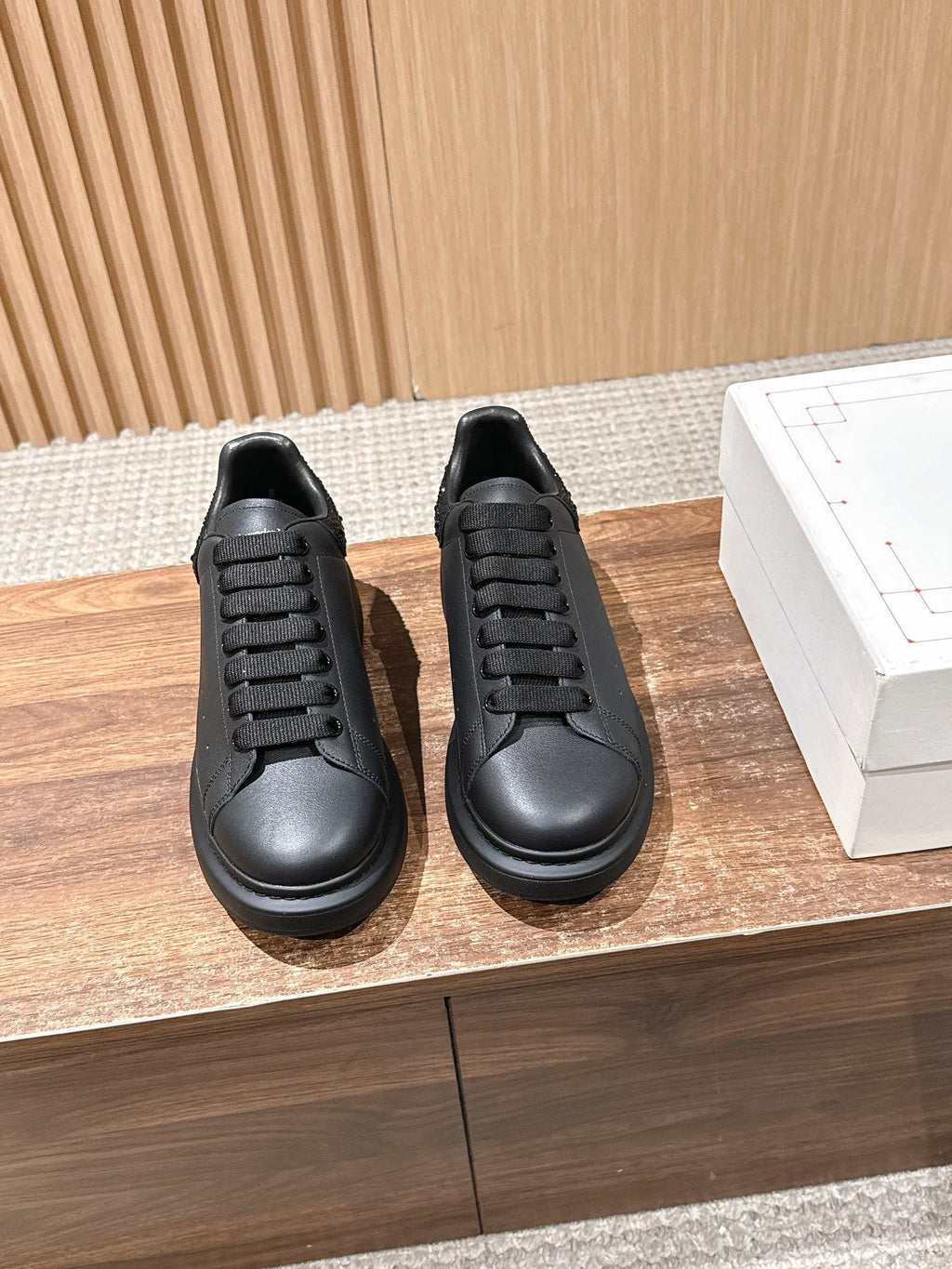 Pair of black leather low-top sneakers with lace-up design and dark rubber soles