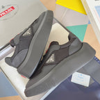 Prada unisex sneakers, dark gray mesh with gray panels, red sole accents, side view